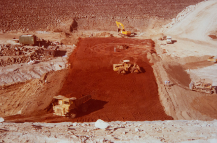 Sepia toned image of yellow excavators clearing dirt. 